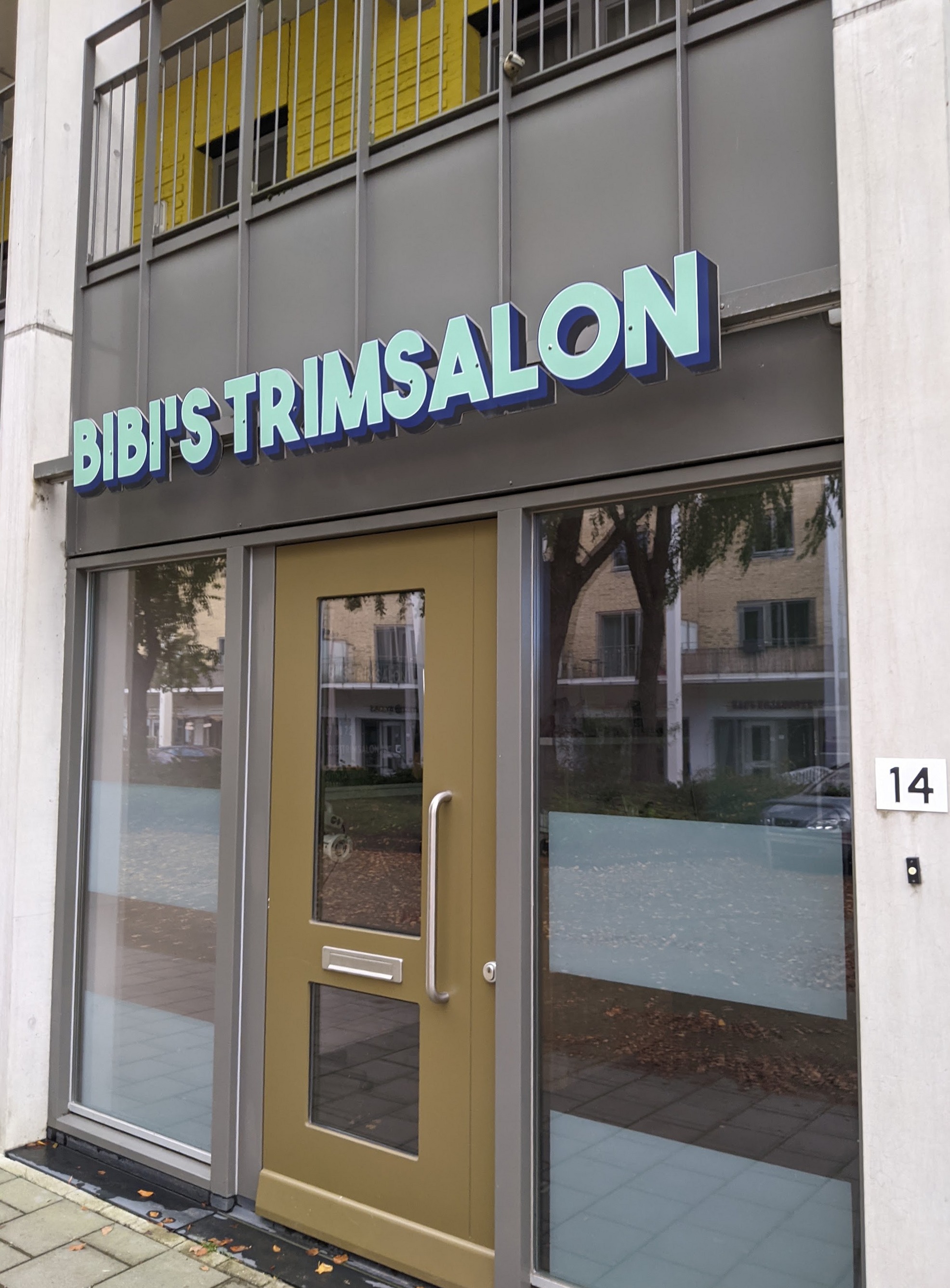 De winkelpui van Bibi's Trimsalon aan de Edisonstraat 14, met mintgroene letters en een olijfgroene deur